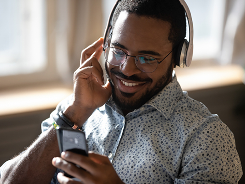 A man wearing headphones smiling looking at his phone