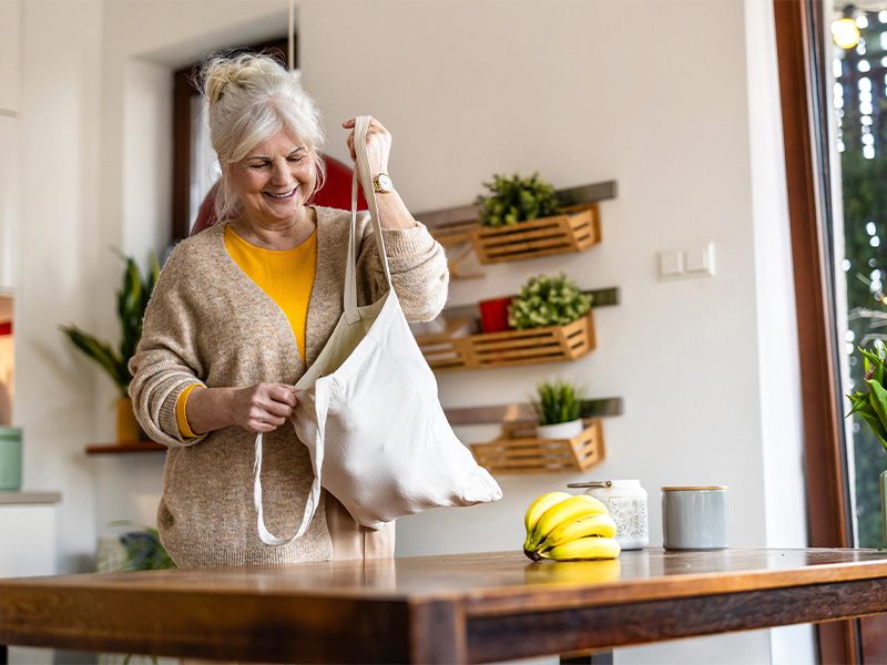 Mature woman unpacking groceries from a cotton reusable bag