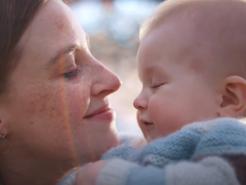 A mother is smiling, with her face close to her baby.
