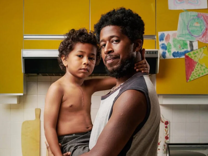 A father is holding his child, who has a scar on his chest.