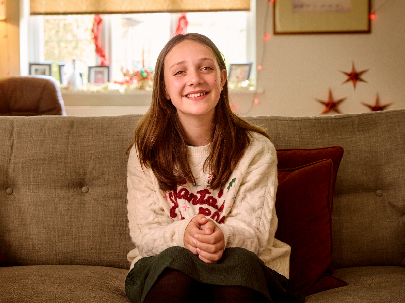 Bea, sat on a sofa smiling