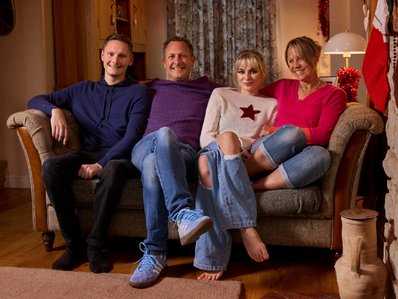 Macy and Monty sat on a sofa with their family