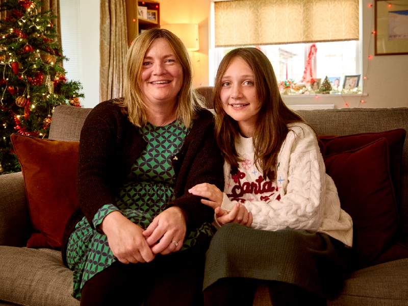 Bea, with her mum Liz sat on a sofa