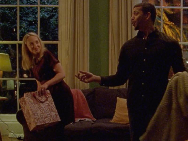 A still from BHF's Christmas TV advert showing two people looking at each other, smiling. One of them is holding a Christmas gift bag.