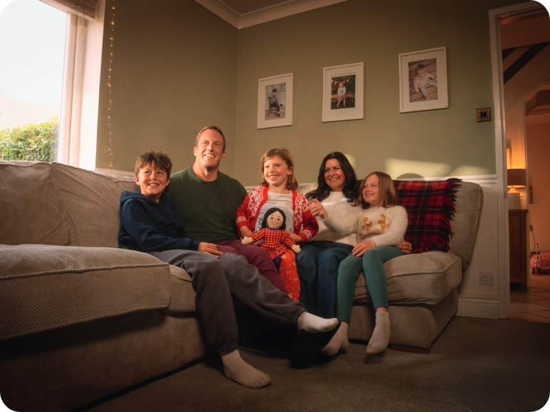 Amalie on the sofa with her parents and siblings either side of her.