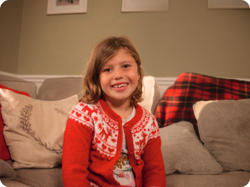  Amalie in front of a beige sofa at home wearing red festive pyjamas.