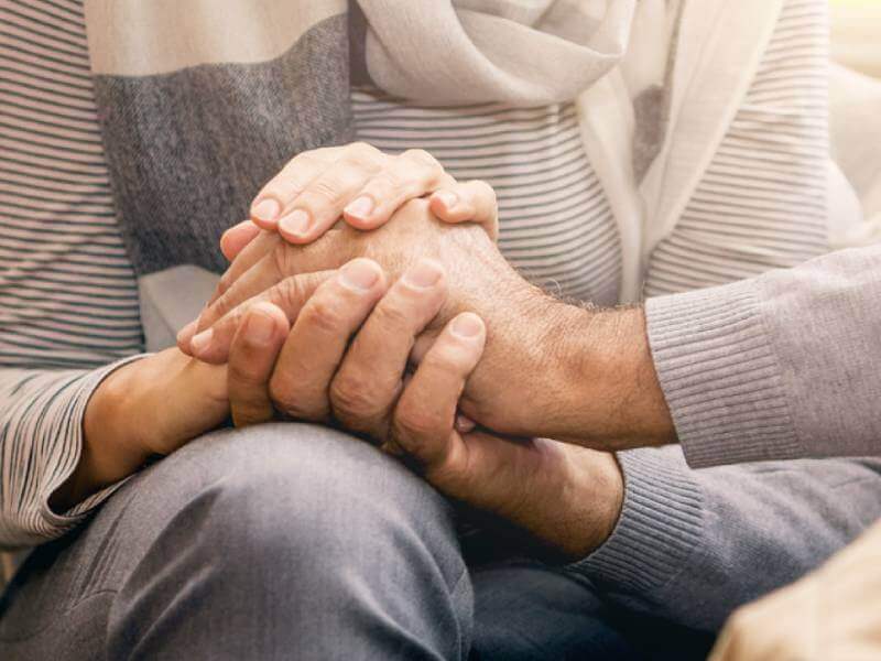 Elderly couples' hands clasped together