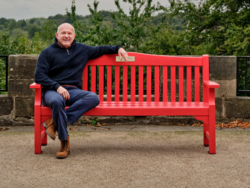 Dean, sitting on a red bench outdoors.