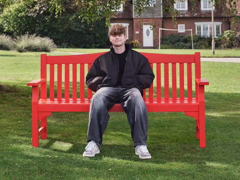 Jack, sitting on a red BHF bench outdoors.