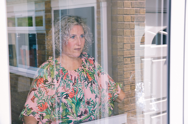 Simone looking out the window wearing a floral top