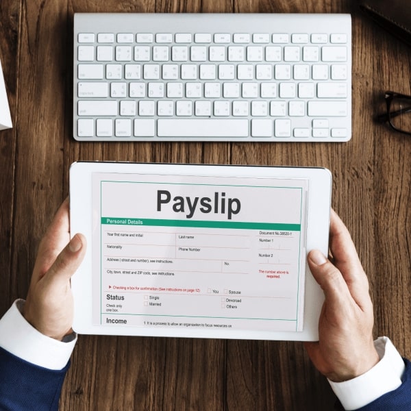 A person looks at their payslip in front of the computer