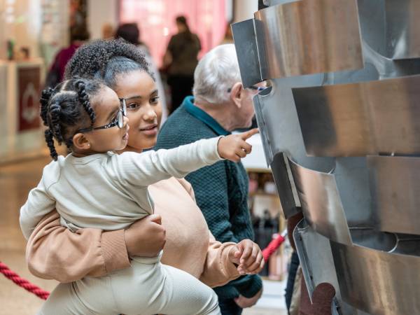 A mother and her daughter reading names engraved on the Heart of Steel