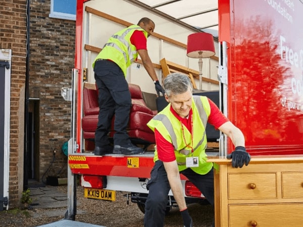 BHF staff move a chest of drawers onto the back of a removal truck.