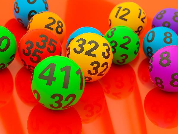 10 brightly coloured lottery balls sat on a red surface