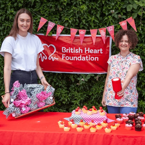 Two people take part in a bake sale for the BHF