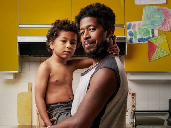 A father holding his son, who has a midline chest scar from heart surgery.