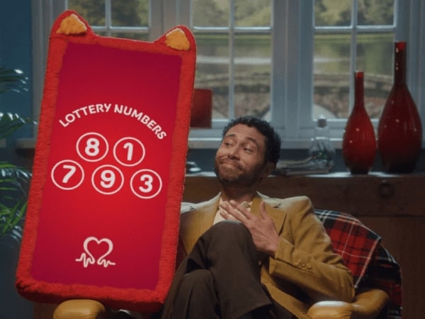 A person next to a large placard showing lottery numbers