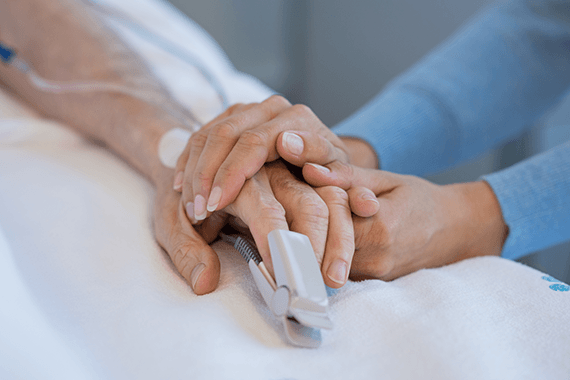 An elderly person has their hand held in hospital
