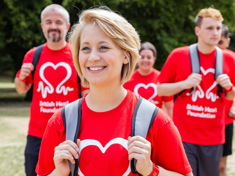 A group of fundraisers are hiking outdoors. They are wearing red BHF t-shirts.