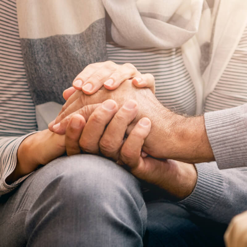 Two people are holding hands in a reassuring manner.