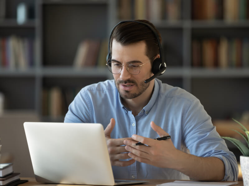 A person talking on a headset while using a computer.