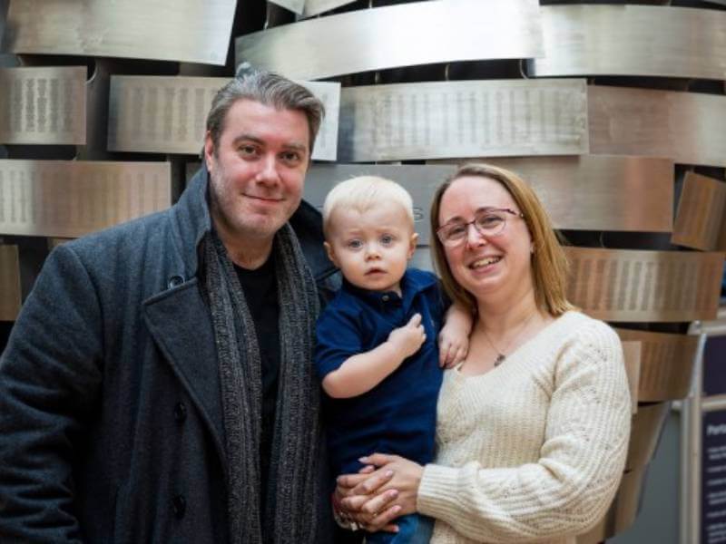 Couple holding small child in front of the Heart of Steel