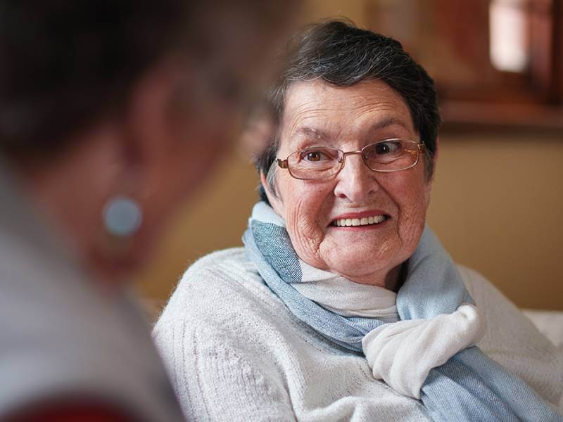 Elderly person smiling at a relative.