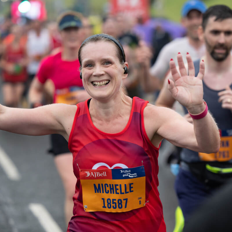 A runner waving to the camera as she participates in an event