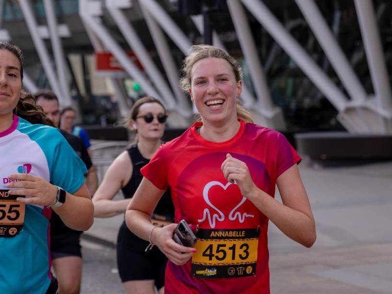 Woman running in a BHF t-shirt amongst other people.
