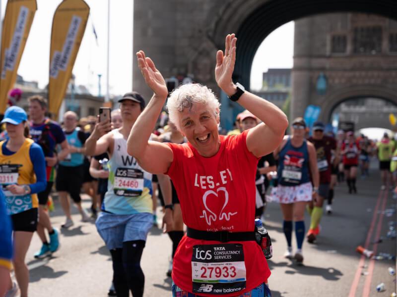 BHF runner clapping and smiling as they run over Tower Bridge