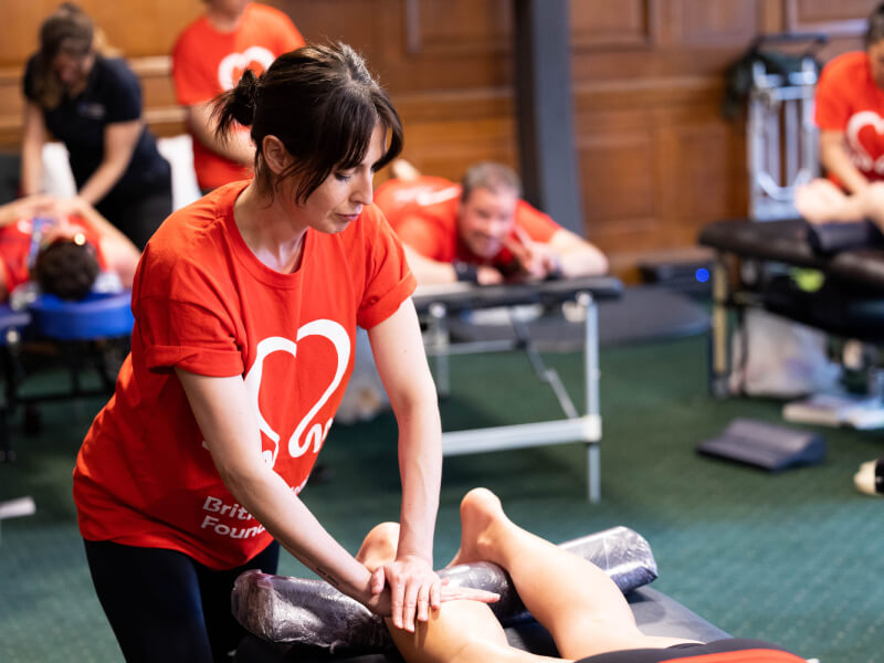 Woman in red BHF t-shirt giving a runner a leg massage