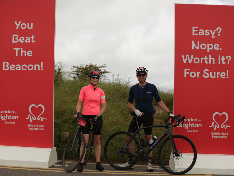 Two bike riders parked next to BHF-branded banners