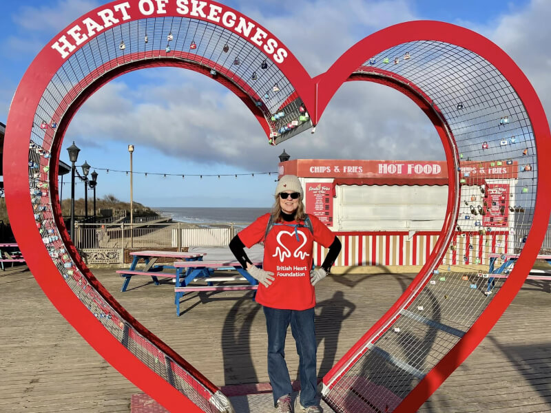 A photograph of Ruth, standing in a heart sculpture.