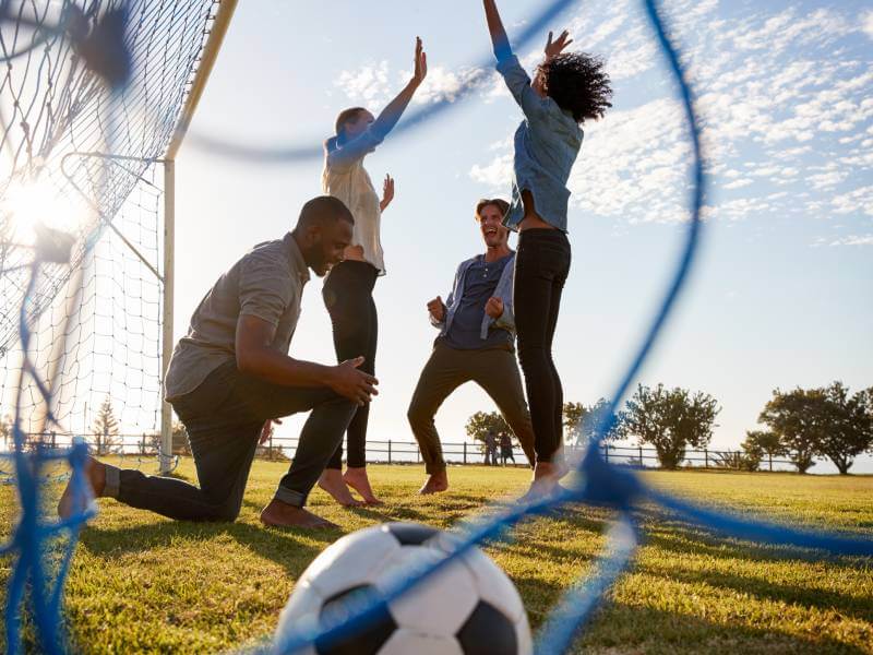 Friends playing a friendly football match outside on the grass