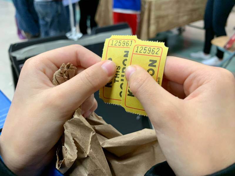 Hands holding two raffle tickets