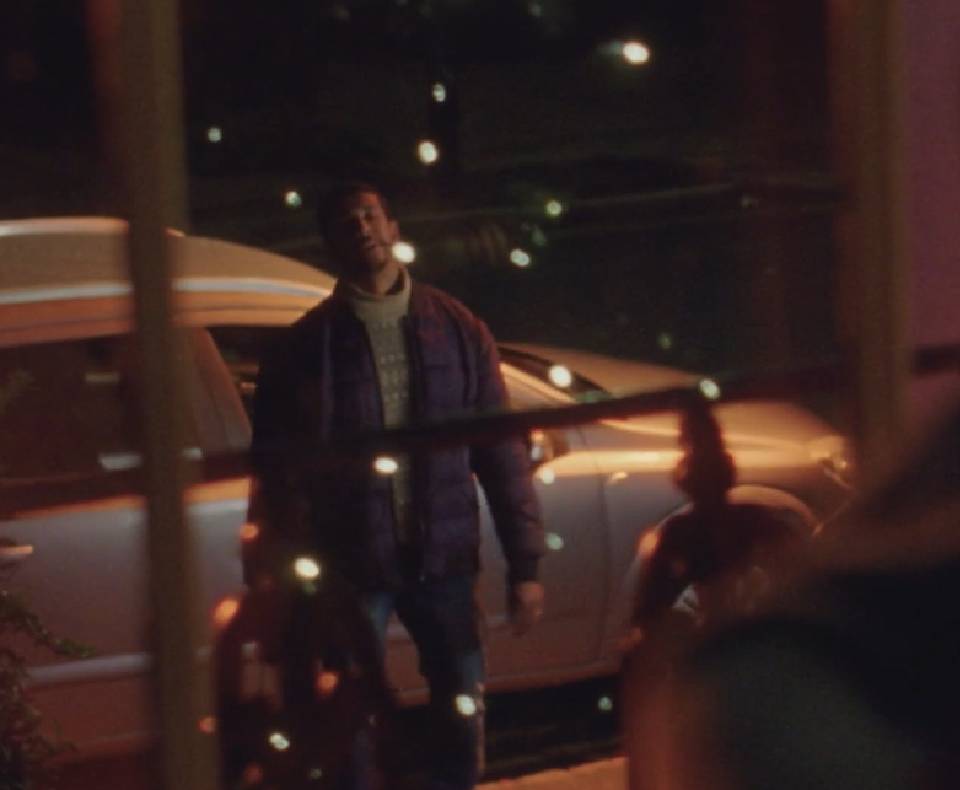 man standing out of a window in the dark in a christmas jumper