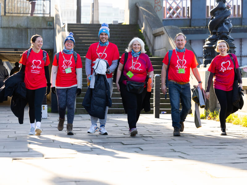 Group of BHF supporters in branded red t-shirts walking along the river Thames