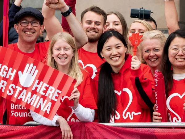 a group of young men and women standing on the sidelines at a BHF event wearing red BHF t shirts and cheering