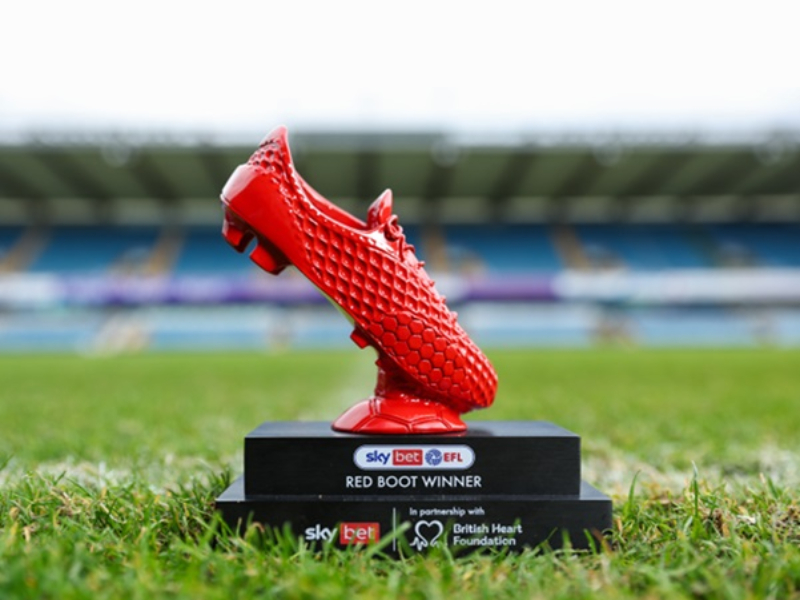 A red, boot-shaped award. It sits on a football pitch.