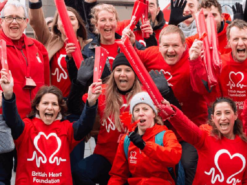 A group of people cheering and waving whilst wearing BHF branded t shirts.