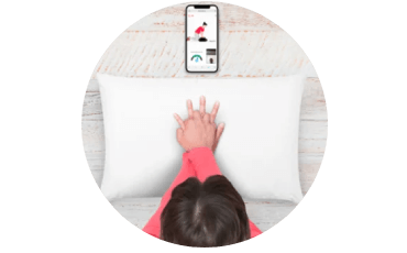 Overhead view of a person using the RevivR training app on a mobile phone, hands clasped over a cushion on the floor.