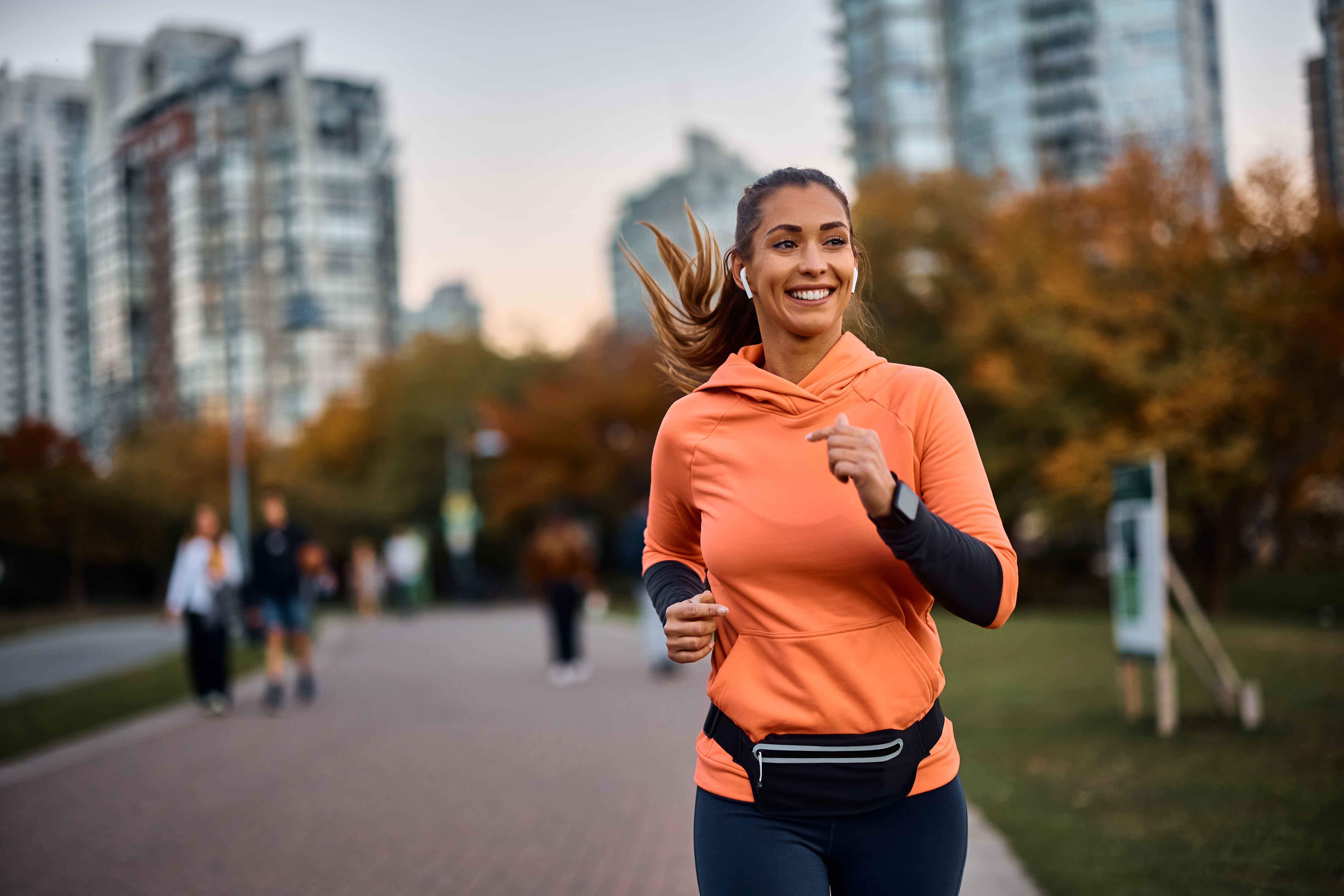 Person running through a park with a skyscrapers in the background
