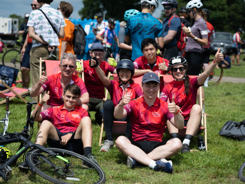 A group of London to Brighton riders sitting on the grass smiling