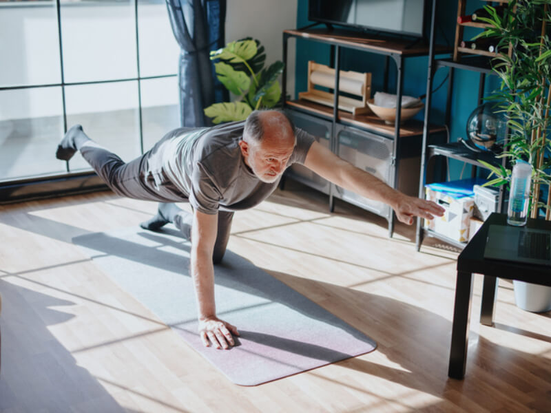 A man practices a yoga move on a yoga mat 