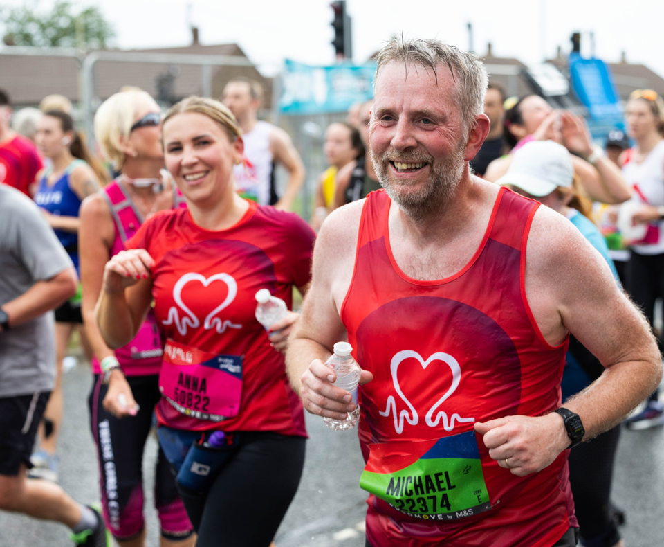 2 people running in a city race wearing BHF jersey