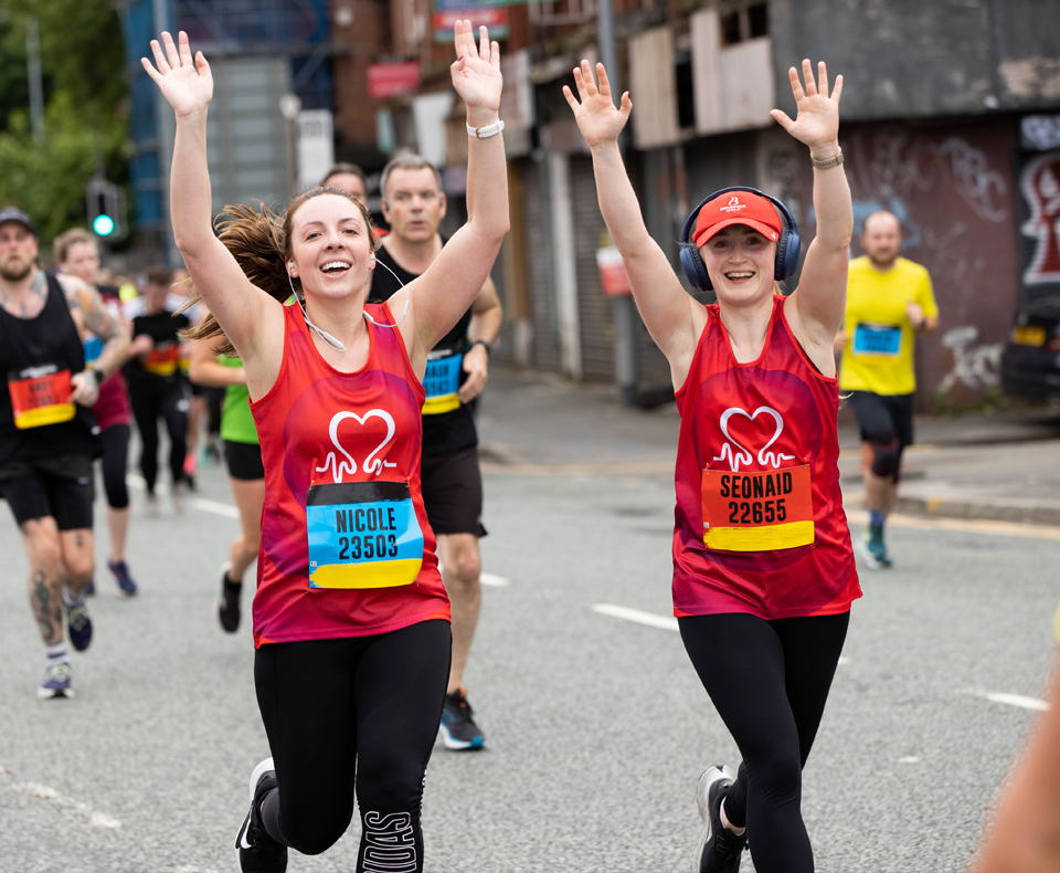 Two people running with arms in the air