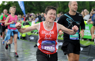An ecstatic lady crosses a marathon finishing line.