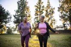 Two ladies walking outside together smiling 