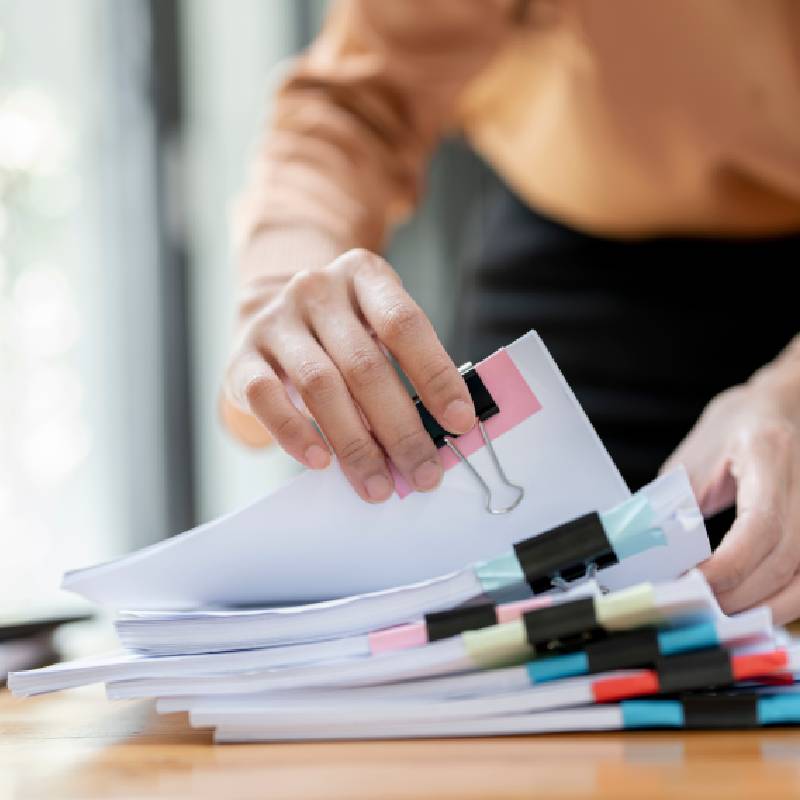 A person holding a pile of forms.