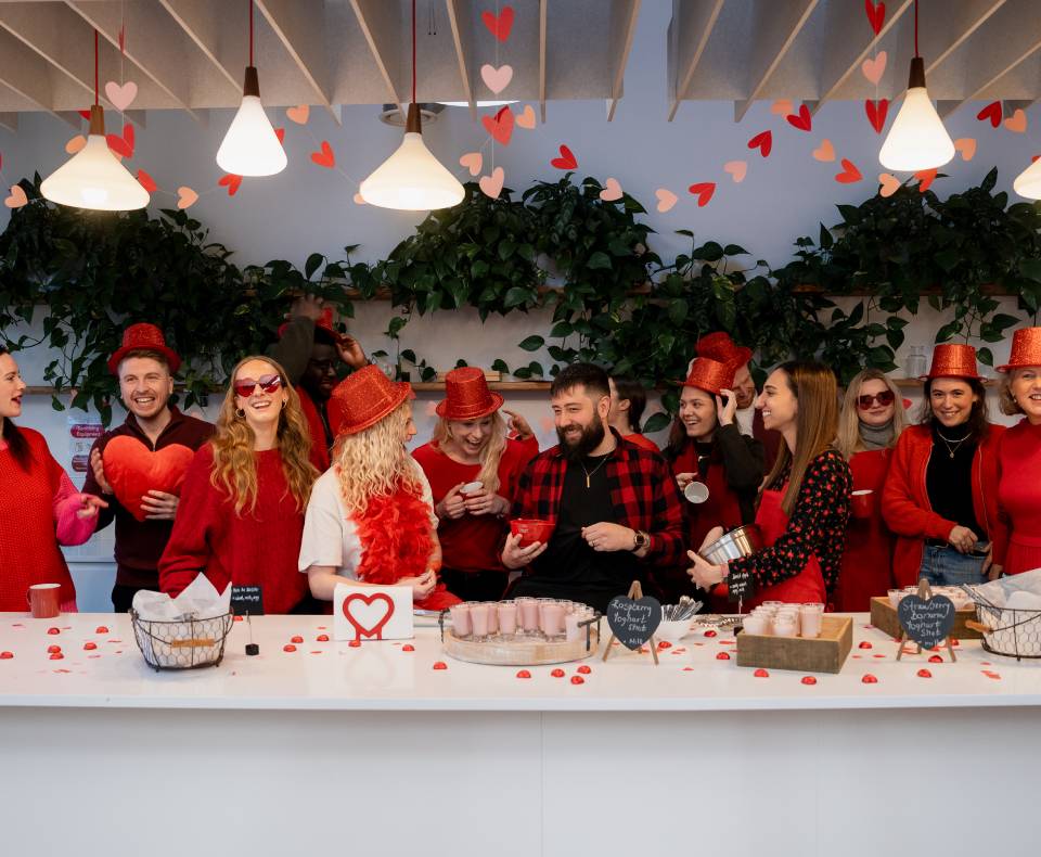 Group of people all wearing red standing around a table with red snacks
